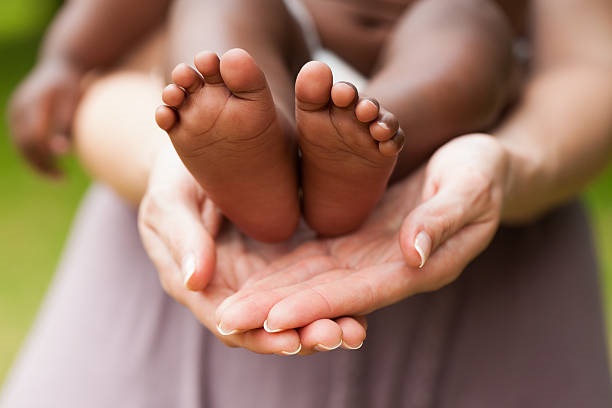Adopted Baby's feet on mothers hands. Horizontal Shot.